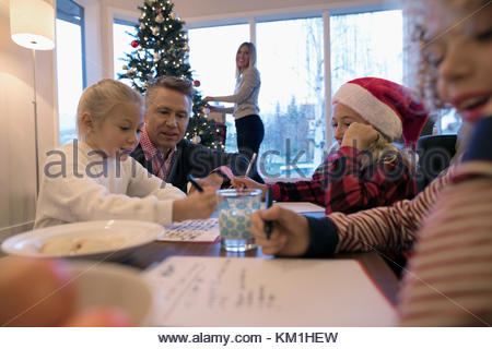 Vater, Tochter und Sohn schreiben Santa Buchstaben in Weihnachten Wohnzimmer