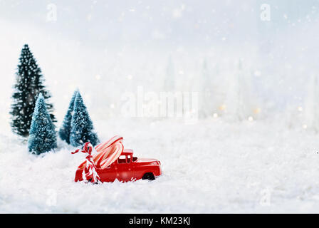 1950 antique Vintage red Lkw schleppen eine zuckerstangen Home durch eine verschneite Winter Wonder Land mit Pinien im Hintergrund. extrem geringen Tiefenschärfe Stockfoto