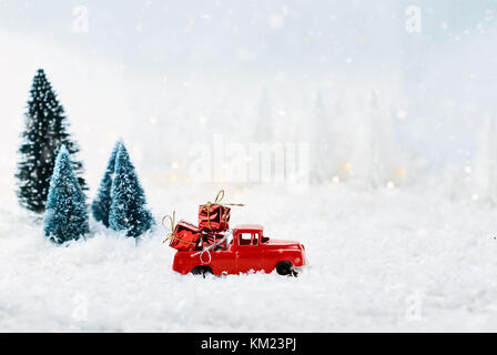 1950 antique Vintage red Lkw schleppen ein Weihnachtsgeschenke nach Hause durch einen verschneiten Winter Wonder Land mit Pinien. Stockfoto