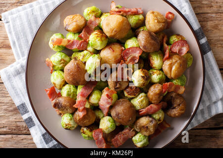 Hausgemachten Salat von gebratenen Kastanien, Rosenkohl und Speck closeup auf einem Teller. horizontal oben Ansicht von oben Stockfoto