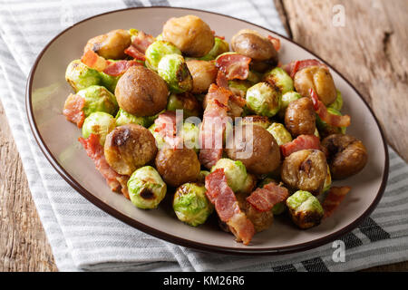 Herzhaften Salat von Kastanien, Rosenkohl und Speck close-up auf einem Teller auf dem Tisch. Horizontale Stockfoto