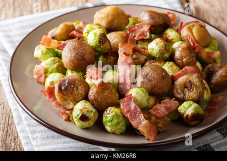 Salat aus gekochten Kastanien, gebratenen Rosenkohl mit Speck close-up auf einem Teller auf dem Tisch. Horizontale Stockfoto