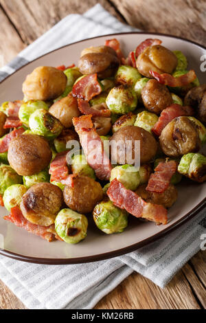 Gebratene Kastanien, Rosenkohl und Speck closeup auf einem Teller. Vertikale Stockfoto