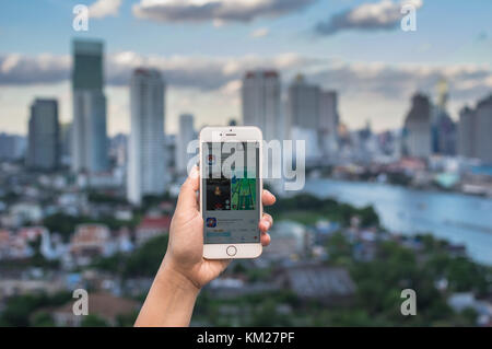 Bangkok, Thailand - 31. Juli 2016: Hand mit Apple iphone 6 Handy die Pokemon gehen, das am Bildschirm über das Bangkok Stadtbild ph Stockfoto