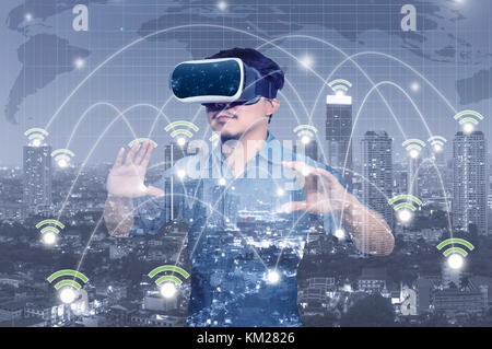 Double Exposure asiatischer Mann tragen Virtuelle Realität mit Netzwerkverbindung zwischen Gebäude der Stadtbild Hintergrund, Business Technology Konzept Stockfoto