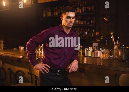 Junger eleganter Mann im Hemd, der an der Theke steht. Nachtleben, Geschäftsmannes Freizeit im Nachtclub Stockfoto