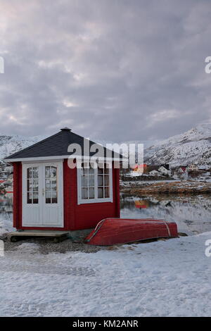 Rot lackiert Ruderboot und Holzhütte mit schwarzem Dach und weißen geschlossenen Tür und Fenster auf hjertholmen islet-e. Begrenzung der Fischereihafen - mounts lodin Stockfoto