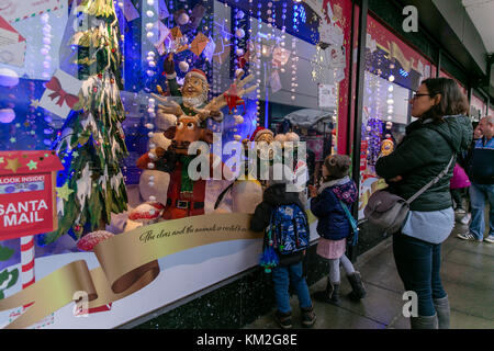 Dublin, Irland. 3 Dez, 2017. Familie bewundern Weihnachten Dekoration in den Fenstern von Arnotts Store auf der Henry Street, Dublin Stockfoto