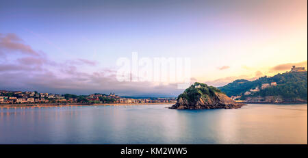 Die berühmten Concha Bucht bei Sonnenuntergang mit dem Monte Igueldo auf der rechten Seite, die Isla de Santa Clara im Zentrum und der Innenstadt von San Sebastian auf der linken Seite. Stockfoto