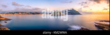 Die berühmten Concha Bucht bei Sonnenuntergang mit dem Monte Igueldo auf der rechten Seite, die Isla de Santa Clara im Zentrum und der Innenstadt von San Sebastian auf der linken Seite. Stockfoto