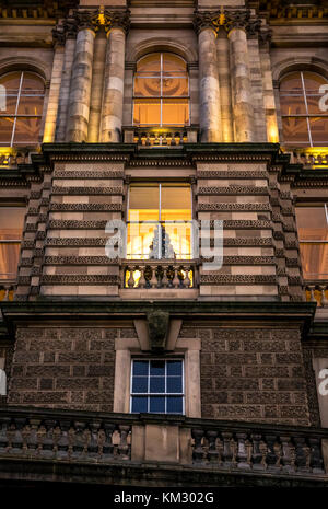 In der Nähe der viktorianischen Gebäude, Bank von Schottland Hauptquartier, die Hügel, die in der Dämmerung mit einem Weihnachtsbaum in Fenster, Edinburgh, Schottland, Großbritannien lit Stockfoto