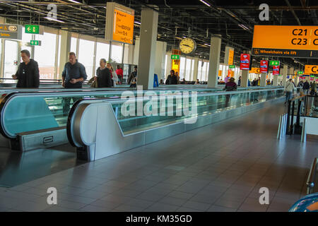 Amsterdam Schiphol, Niederlande - 18. April 2015: Innenraum des Amsterdamer Flughafens Schiphol. Passagiere auf einer langen horizontalen Rolltreppe Stockfoto