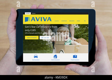 Ein Mann sieht im Aviva Website auf seinem iPad tablet device, Schuß gegen einen hölzernen Tisch top Hintergrund (nur redaktionelle Nutzung) Stockfoto