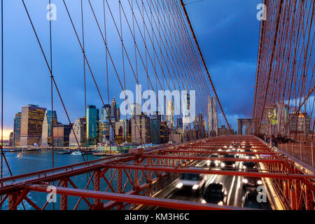 Autos Beschleunigung bei Sonnenuntergang auf der Brooklyn Bridge und Manhattan. Eine der berühmtesten Brücken der Welt, eine Attraktion sehen muss bei einem Besuch in New York. Stockfoto
