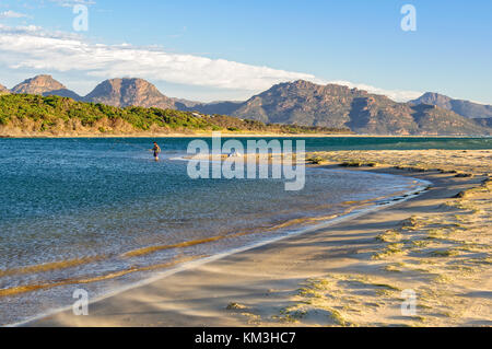 Ein angler im flachen Wasser auf der 9 Mile Beach in der Nähe von Swansea mit den Freycinet National Park in der Ferne - Tasmanien, Australien Stockfoto