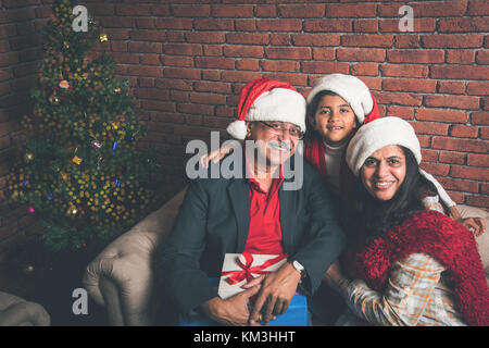 Familie, Urlaub, Generation, Weihnachten und Personen Konzept - lächelnd indischen Großeltern und Enkelin mit geschenkboxen Sitzen auf der Couch zu Hause Stockfoto