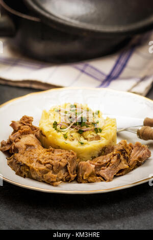 Confit Schweinekamm mit Kartoffelpüree auf steinernen Tisch Stockfoto