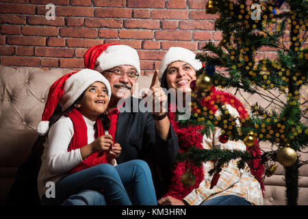 Familie, Urlaub, Generation, Weihnachten und Personen Konzept - lächelnd indischen Großeltern und Enkelin mit geschenkboxen Dekorieren Weihnachtsbaum Stockfoto