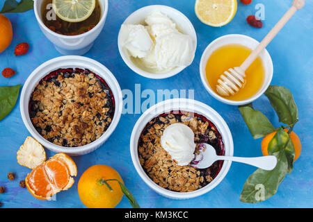 Winter Frühstück mit Berry bröckeln und Tee mit Zitrone. blauen Hintergrund. Stockfoto