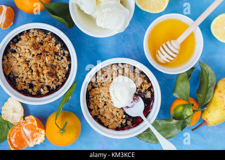 Winter Frühstück mit Berry bröckeln und Tee mit Zitrone. blauen Hintergrund. Stockfoto