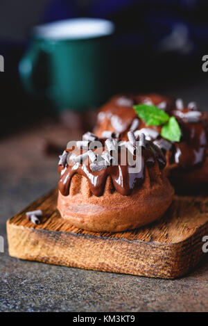 Mini Schokolade bundt Cake mit Ganache und minzeblatt auf Holz Schneidebrett. Detailansicht, selektiver Fokus Stockfoto