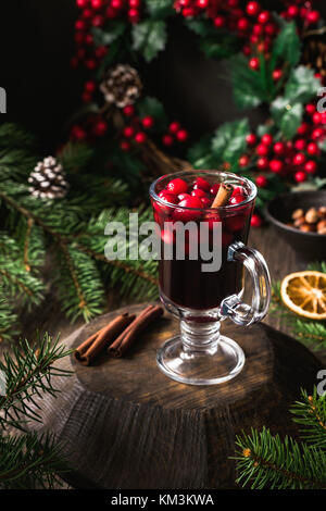 Wein mit Preiselbeeren und Zimt in Glas auf Holzbrett Glühwein. Heiße Weihnachten trinken, noch Leben. Selektiver Fokus Stockfoto