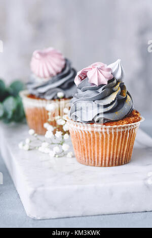 Cupcakes mit grauen buttercream Frosting und Baiser Küsse auf Marmor. Detailansicht. Hochzeitstorten Stockfoto