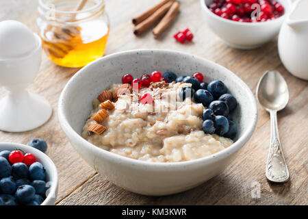 Gesundes Frühstück essen Haferflocken Porridge, gekochtes Ei, Honig und Beeren. Mahlzeit für Kinder, Diät oder gesunden Lebensstil Konzept Stockfoto