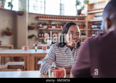 Junge afrikanische Frau lachend mit Ihrem Datum in einem Cafe Stockfoto