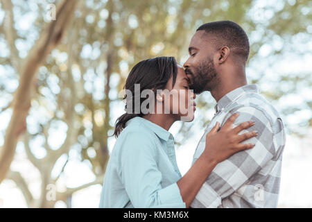 Romantische junge afrikanische Mann küssen Stirn draußen seiner Freundin