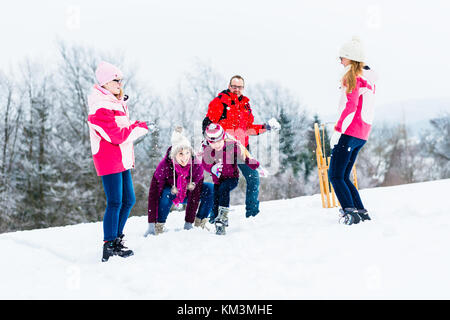 Familie mit Kindern in Schneeballschlacht im Winter für Spaß Stockfoto