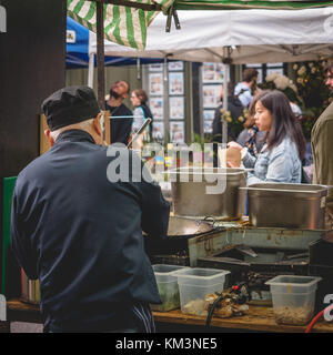 Thai koch Zubereitung von Speisen in einer Straße Essen in Broadway Marktstand. East London (UK), August 2017. Quadratischen Format. Stockfoto