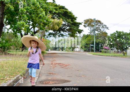 Junge Mädchen mit einem Sombrero zu Fuß in einer Vorstadtstraße, Townsville, Queensland, Australien Stockfoto