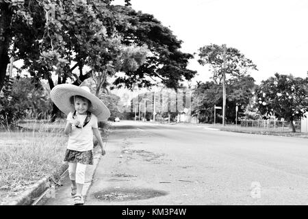 Junge Mädchen mit einem Sombrero zu Fuß in einer Vorstadtstraße, Townsville, Queensland, Australien Stockfoto