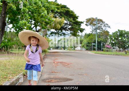 Junge Mädchen mit einem Sombrero zu Fuß in einer Vorstadtstraße, Townsville, Queensland, Australien Stockfoto