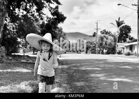 Junge Mädchen mit einem Sombrero zu Fuß in einer Vorstadtstraße, Townsville, Queensland, Australien Stockfoto