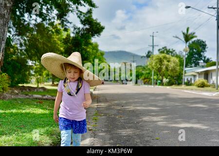 Junge Mädchen mit einem Sombrero zu Fuß in einer Vorstadtstraße, Townsville, Queensland, Australien Stockfoto