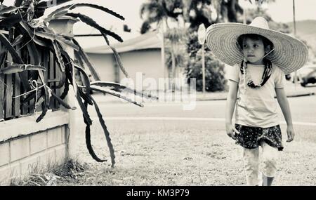 Junge Mädchen mit einem Sombrero zu Fuß in einer Vorstadtstraße, Townsville, Queensland, Australien Stockfoto