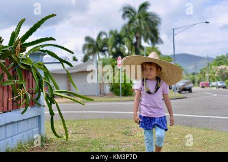 Junge Mädchen mit einem Sombrero zu Fuß in einer Vorstadtstraße, Townsville, Queensland, Australien Stockfoto