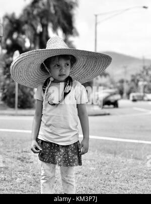 Junge Mädchen mit einem Sombrero zu Fuß in einer Vorstadtstraße, Townsville, Queensland, Australien Stockfoto