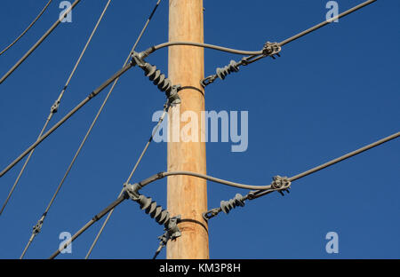 Nahaufnahme der brandneue Holz Pole und Stromleitungen in neue Entwicklung mit Isolatoren gegen den blauen Himmel Stockfoto