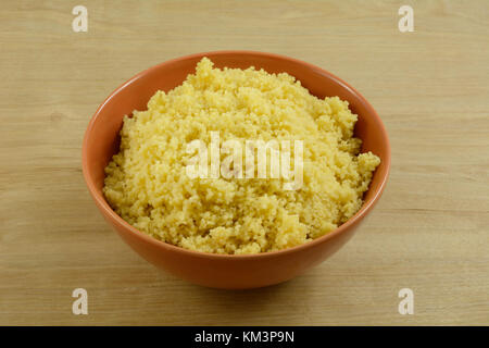 Gekochten couscous Beilage in der orange bowl auf hölzernen Tisch Stockfoto