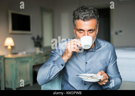 Reifen Geschäftsmann Kaffee trinken in einem Hotelzimmer. Stockfoto