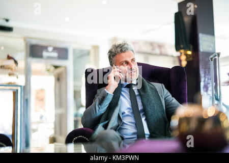 Reifen Geschäftsmann mit Smartphones in der Hotel Lounge. Stockfoto