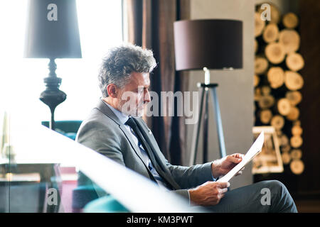 Reifen Geschäftsmann Lesung in der Lounge des Hotels. Stockfoto