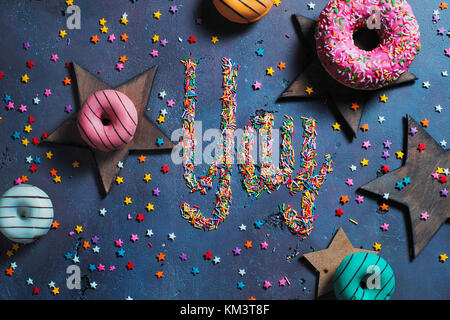 Ausrufezeichen Yay mit schriftlicher Streusel auf einem Stein mit Donuts und Sterne. Party Vorbereitung Konzept. Stockfoto