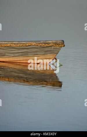 Holzboot mit Reflexion über Wasser, Schilf Banken im Hintergrund. Kopieren Platz Oben und Unten. Stockfoto