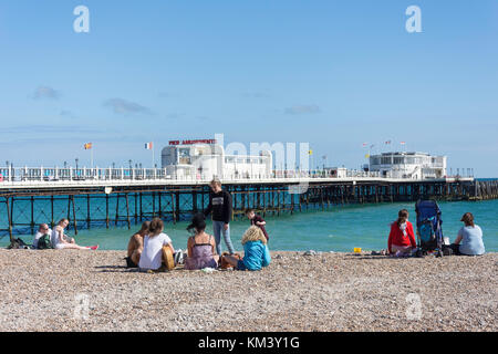 Junge Gruppe am Strand mit Worthing Pier hinter, Worthing, West Sussex, England, Vereinigtes Königreich Stockfoto