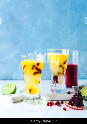 Zwei Gläser alkoholfreien Cocktail mit Orangenlikör, frisch gepresste Ananas und Granatapfelsaft und Kalk und Eis auf dem Tisch. Stockfoto