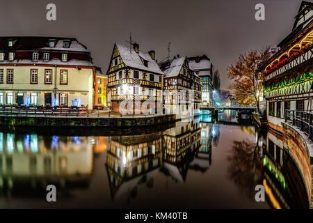 Alte Fachwerkhäuser framing Häuser im Viertel Petite France, Straßburg. schneebedeckte Dächer und refctions im Fluss Wasser. Nacht Szene. Weihnachtszeit. Stockfoto